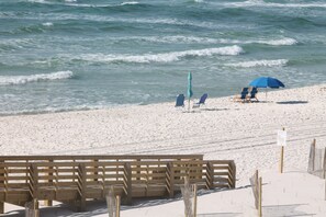 A beach with wooden benches and two blue umbrellas. - Fall at the beach is amazing ! Same beautiful beach, great weather & NO crowds (Orange Beach)