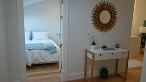 Ein Schlafzimmer mit einem Bett, einem Nachttisch mit Spiegel und einer Zimmerpflanze.
