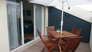 Ein Holz-Esstisch mit Stühlen auf einem Balkon, mit einer Schiebeglastür zum Wohnbereich.