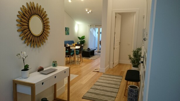 Ein modernes Wohnzimmer mit Essbereich, einem großen Spiegel und einer Zimmerpflanze.