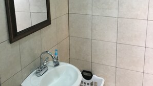 A bathroom with a sink, mirror, and two signs reading "BAHT" and "BATH".