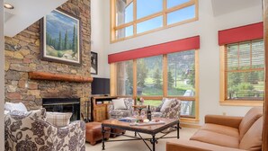 A cozy living room with a stone fireplace, large windows, and comfortable seating. - RMR: Cody House C Condo in Teton Village (Teton Village)