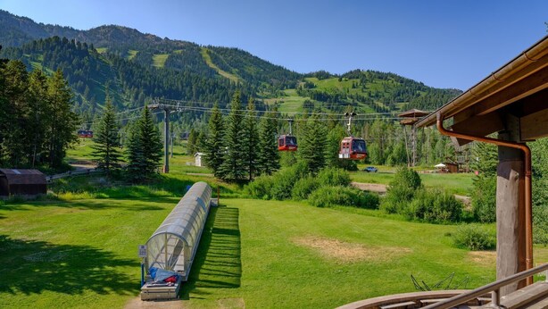 A scenic view of a mountain with a cable car system, a greenhouse, and a wooden building structure. - RMR: Cody House C Condo in Teton Village (Teton Village)