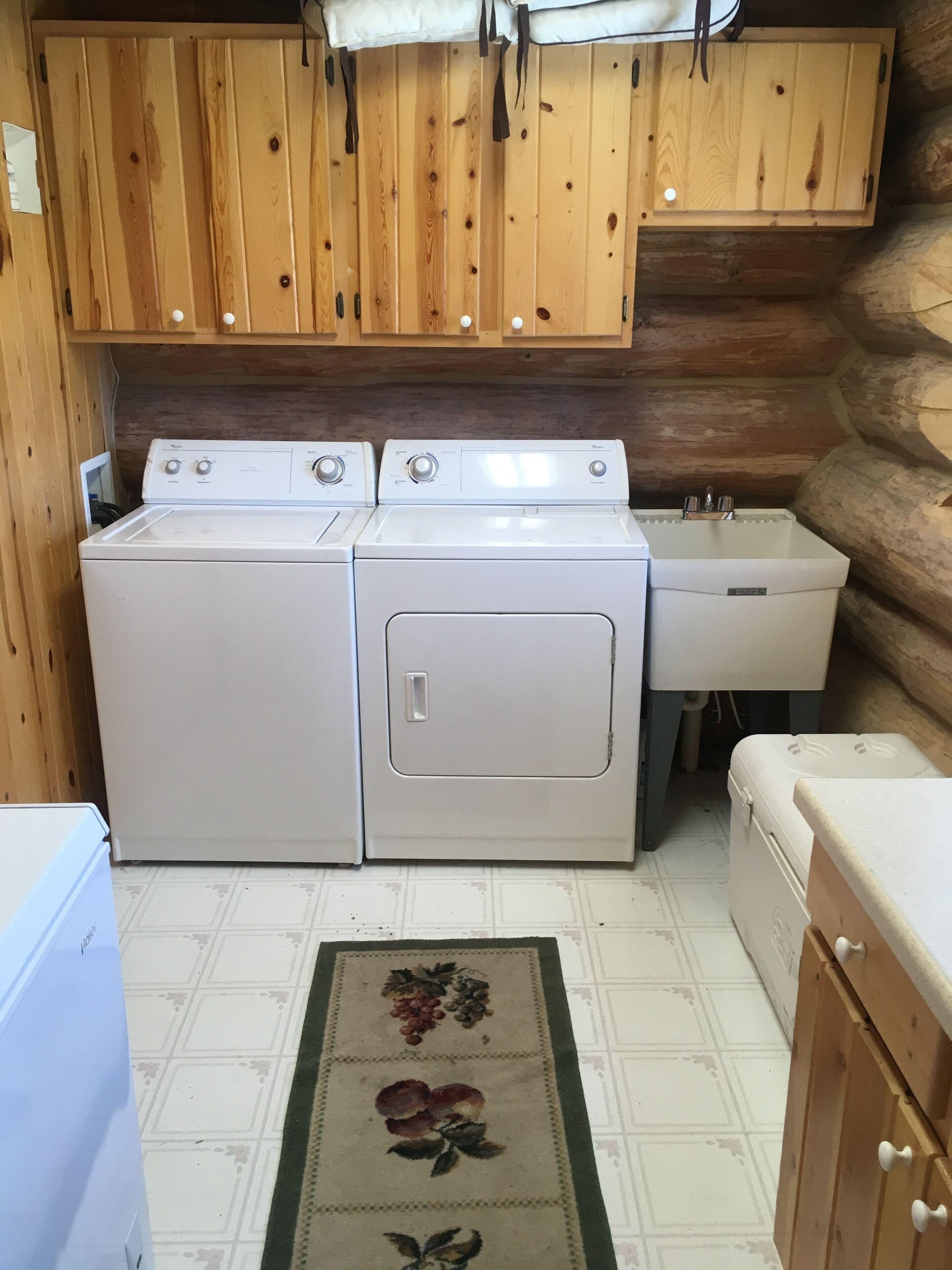 Cocina compacta con armarios de madera, lavadora, lavaplatos y encimera.