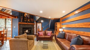 Ein gemütliches Wohnzimmer mit Kamin, Ledersofas und einer Wand aus Holzpaneelen.