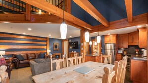 Eine moderne Küche mit Holzschränken, einem Edelstahlkühlschrank und einem Essbereich mit Holztisch und -stühlen.