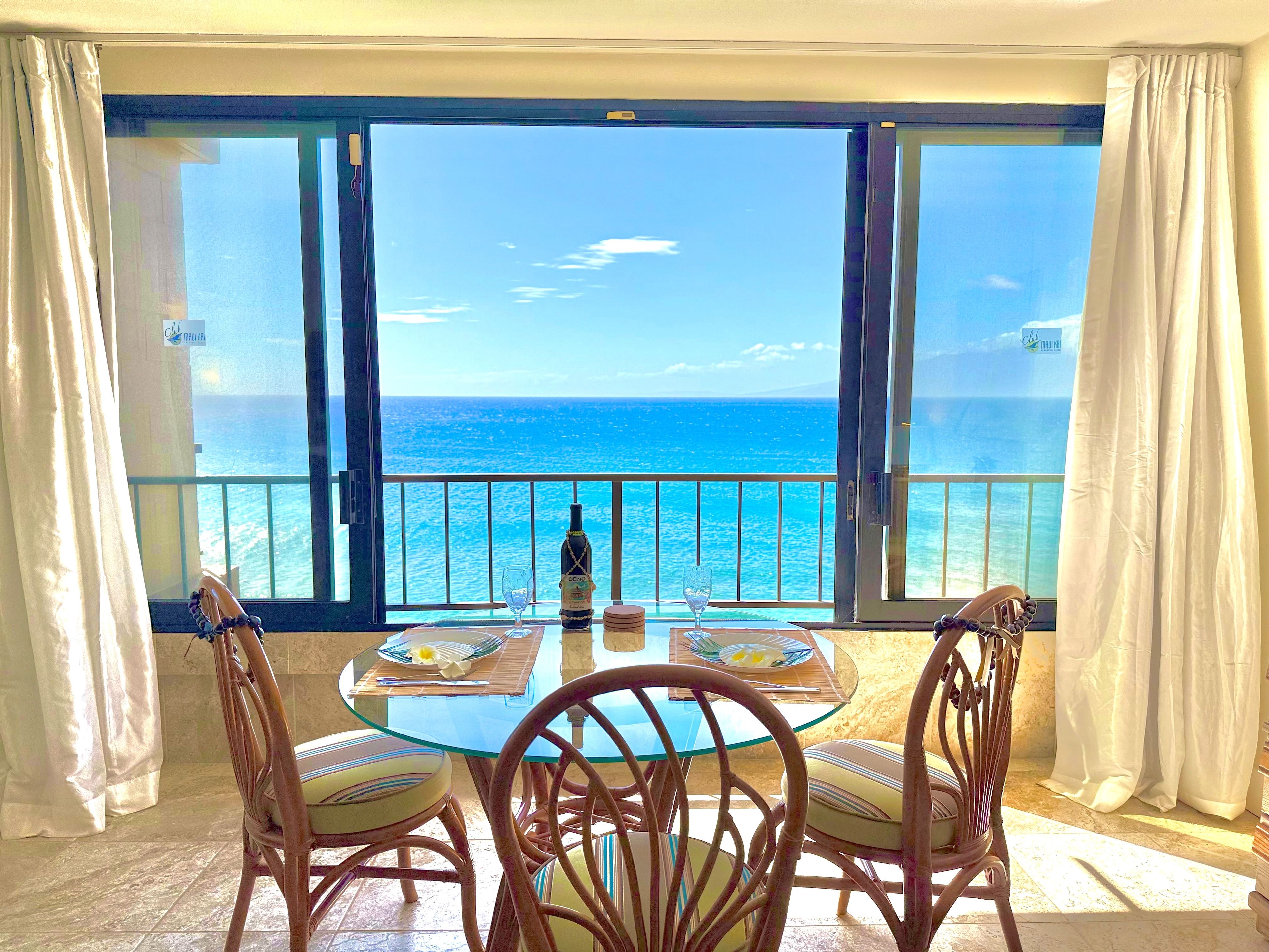 A table with chairs and a bottle of wine, overlooking a sea view.