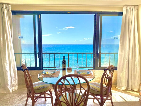 A table with chairs and a bottle of wine, overlooking a sea view.