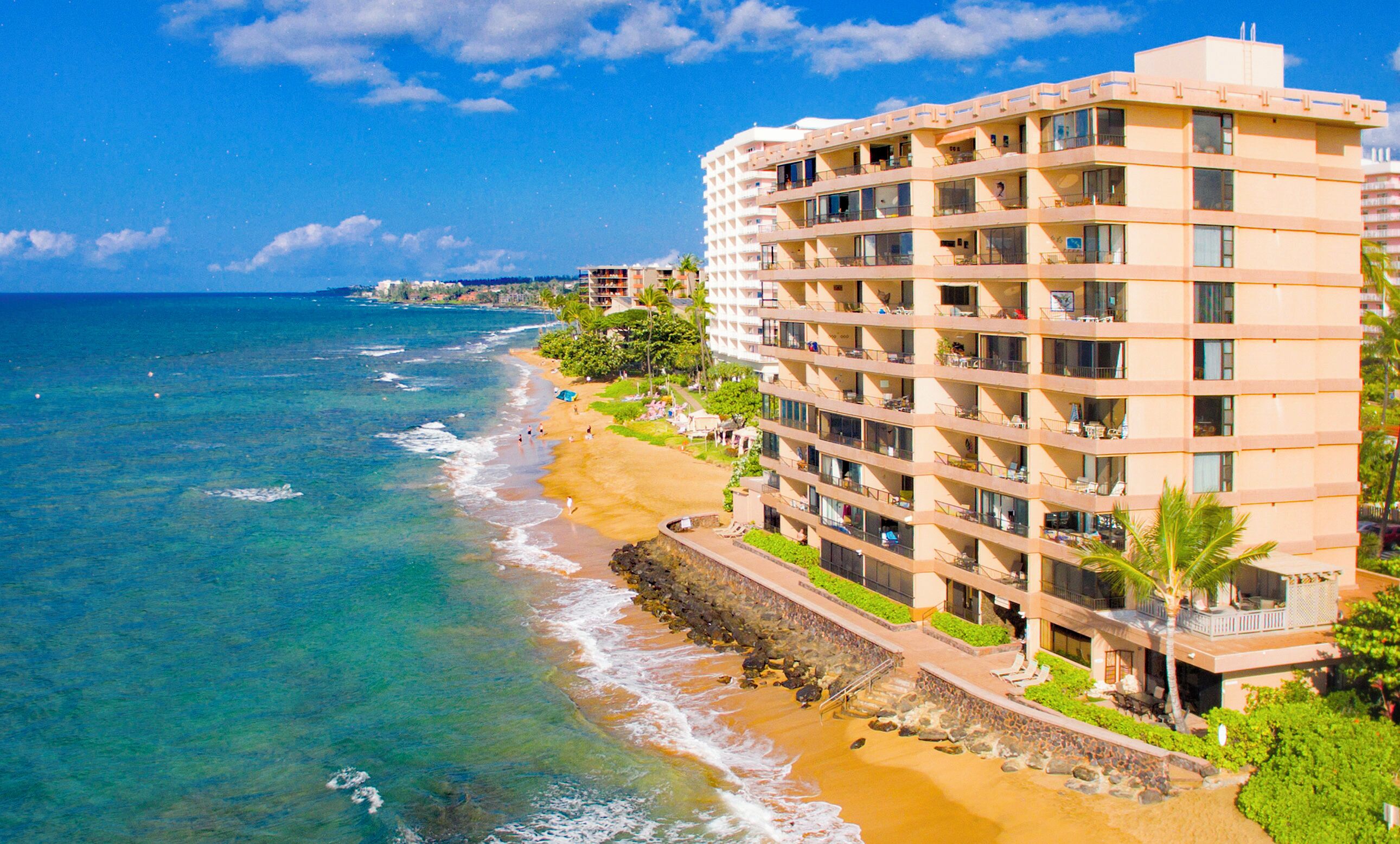 Ein Strandhotel mit mehreren Balkonen, einem Sandstrand und Meerblick.