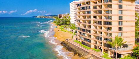 Ein Strandhotel mit mehreren Balkonen, einem Sandstrand und Meerblick.