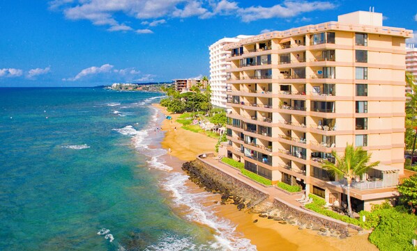 A beachfront hotel with multiple balconies, a sandy beach, and ocean views.