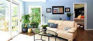 A living room with a sofa, a glass coffee table, and potted plants.