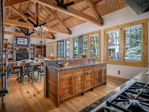 A spacious kitchen with a large island, wooden beams, and large windows.