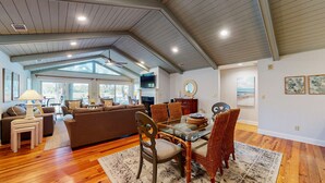 A spacious living room with a large sofa, a dining table with chairs, and a television. - Golf course and lagoon views! (Hilton Head)