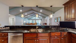 A spacious kitchen with wooden cabinets, a stainless steel sink, and pendant lighting. - Golf course and lagoon views! (Hilton Head)