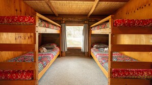 Eine Holzhütte mit Etagenbetten, Teppichboden und einem fenster mit Vorhängen.