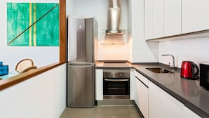 A modern kitchen with a stainless steel refrigerator, built-in oven, and a glass range hood.
