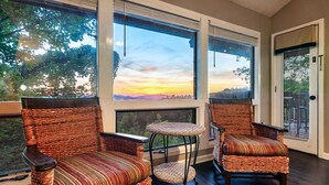 A room with wicker furniture, large windows, and a view of a sunset. - Incredible Views! Massage Chairs, Hot-tub, WiFi (Gatlinburg)