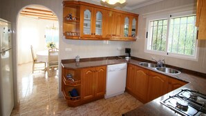 A kitchen with wooden cabinets, a built-in dishwasher, a gas stove, and a window with a view of greenery.