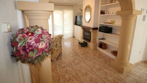 A living room with a fireplace, a sofa, a coffee table, and a floral arrangement.