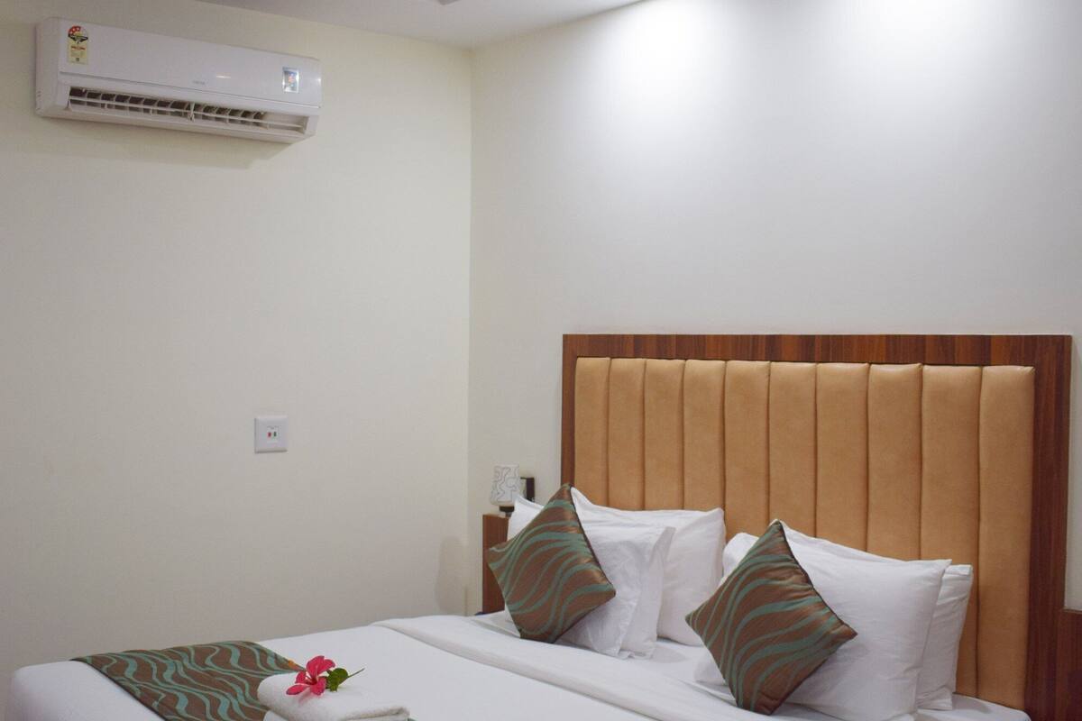 Una cama bien hecha con un cabecero de madera, un ventilador de techo y un equipo de aire acondicionado en la pared.