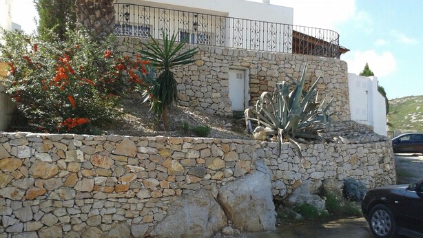 A stone wall with a car parked in front. - Residencial Itxaso 8 LEK (Peñiscola)