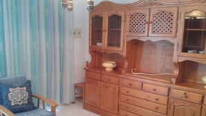 A living room with a wooden cabinet, a blue sofa, and a glass coffee table. - Residencial Itxaso 8 LEK (Peñiscola)