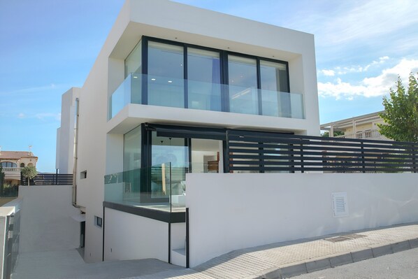A modern two-story building with large windows and a glass balcony. - Atzur Plus 177 modern villa with private pool, air-conditioning, gym and BBQ (Son Serra de Marina)