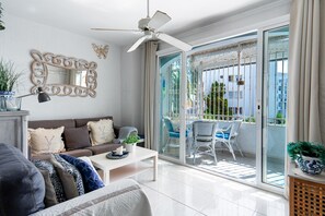 Un salon moderne avec un canapé, une table basse et un ventilateur de plafond.