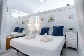 Une chambre à coucher moderne avec un grand lit, deux tables de chevet, un miroir et une petite plante en pot.