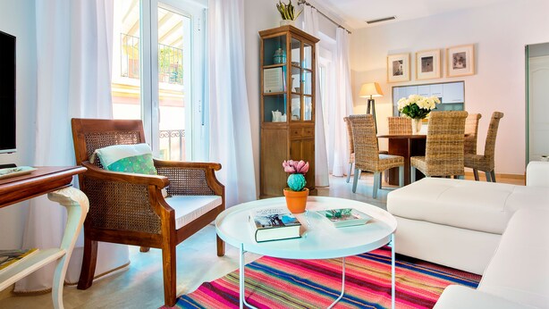 Un salon comprenant un canapé, une table à manger avec des chaises, un téléviseur et une bibliothèque.