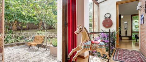 Una habitación con un banco de madera, un caballo balancín y una cortina roja.