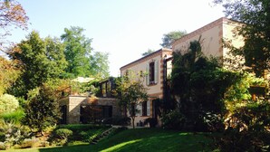 A building with a stone facade, a covered patio, and a well-maintained garden. - Superb architect-designed villa in Fontainebleau -1h from Paris (Larchant)