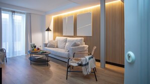 A modern living room with a sofa, a coffee table, a wicker chair, and a lamp. - Singular Stays Mercado Central V (Valencia / València)
