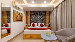 A modern hotel room with a large bed, a ceiling fan, a round table, and a sofa. - RR Residency (New Delhi)