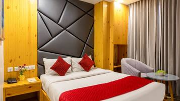 Una habitación de hotel moderna con una cama grande, cabecera de madera, un escritorio con lámpara y una silla.