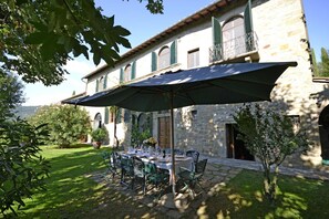 An outdoor dining area with a table set for four, surrounded by green chairs, under a large umbrella. - Villa in Cortona with 6 bedrooms sleeps 12 (Cortona)