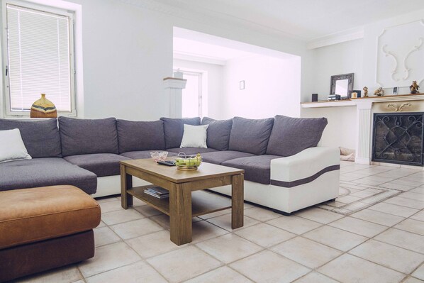 A living room with a sectional sofa, a wooden coffee table, and a fireplace. - Real Slovakia Experience in the Castle View Village House - live like a local (Krásnohorské Podhradie)