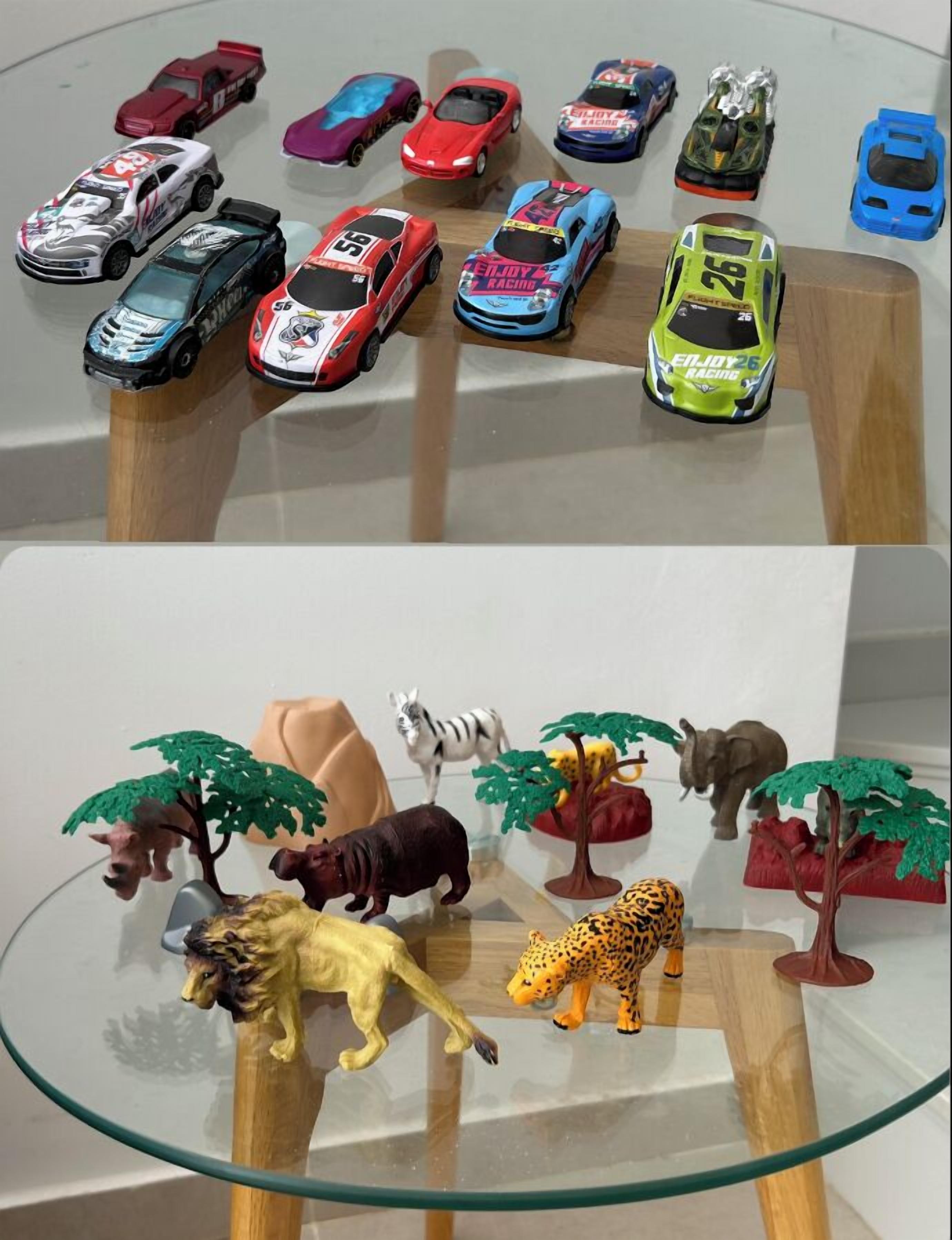 A collection of toy cars and animal figurines on a glass table.