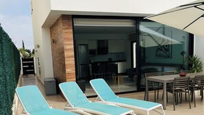 Ein modernes Haus mit Swimmingpool, Liegestühlen und Essbereich.