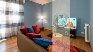 Una sala de estar con un sofá, una lámpara, un televisor y un radiador.