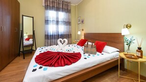Habitación de hotel con cama, mesita de noche, espejo, ventana con cortinas y armario de madera.