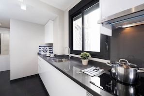 Una cucina moderna con un piano di lavoro nero, elettrodomestici in acciaio inossidabile e una finestra vista edificio.