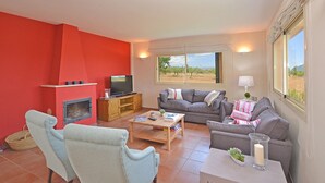 A living room with a fireplace, a sofa, a coffee table, and a television. - Ses Nines - Charming country house with pool in Inca, Mallorca (Inca)