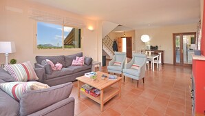 A spacious living room with a grey sofa, a wooden coffee table, and a dining area with a white table and chairs. - Ses Nines - Charming country house with pool in Inca, Mallorca (Inca)