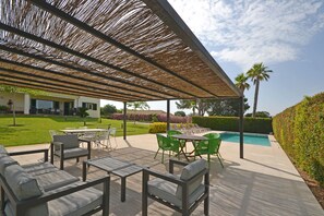 An outdoor patio area with a pool, seating, and a covered section with a thatched roof. - Ses Nines - Charming country house with pool in Inca, Mallorca (Inca)