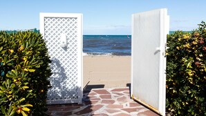 A beach entrance with a white door and a view of the ocean.