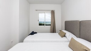 A hotel room with two beds, a window with a view, and a curtain.