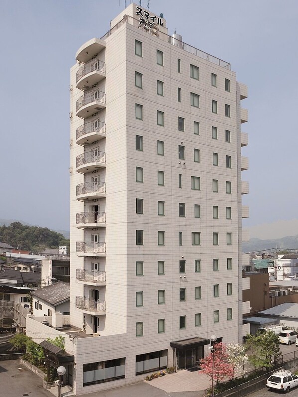 A multi-story hotel with balconies on the upper floors, a flat facade, and a clear sky in the background.