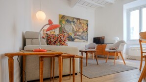 A modern living room with a sofa, a wooden table, a red lamp, and a colorful abstract painting on the wall. - Via Crispi Spanish Steps Apartment. New right in the central elegant and quiet (Roma)